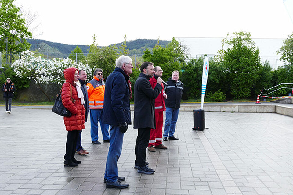 Einige Menschen stehen auf einem Platz und halten kurze Reden zur Eröffnund der Landesmeisterschaften der Wasserwachten Thüringen und Sachsen.